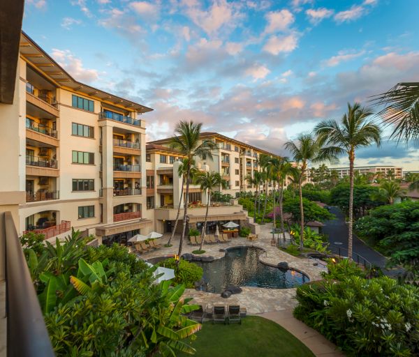 The image shows a tropical resort with palm trees, a swimming pool, and stylish buildings under a colorful sky. A serene getaway spot.